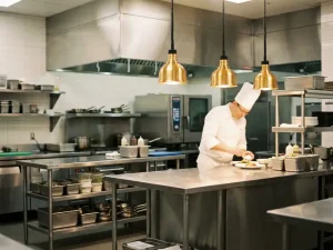 Professionele roestvrijstalen ziekenhuiskeuken met glanzende werkbladen, terwijl een chef in wit uniform maaltijden bereidt op de achtergrond.